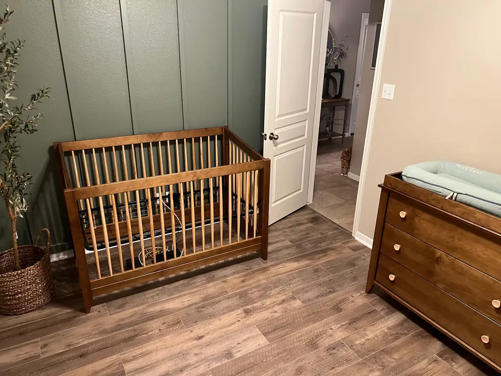 Nursery with new waterproof luxury vinyl plank flooring and a sage board-and-batten wall