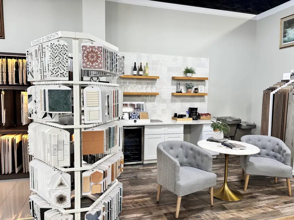 The design consultation area at Bell County Flooring — two grey chairs, a marble table, tile samples and the coffee bar